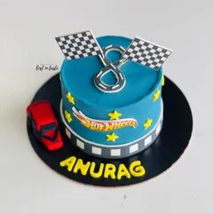 A Hot Wheels themed cake for a young racing fan. This design features a vibrant blue buttercream, the Hot Wheels logo, checkered flags, and a toy car.