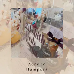 A closer look at our custom acrylic invitation hampers. The transparent design beautifully showcases the curated items inside, while the personalized text with the couple's names adds a modern, elegant touch.