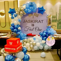 A "Fast One" race car theme for a first birthday. This setup features a custom backdrop, a balloon semi-arch in blue and silver, and a small race car prop.