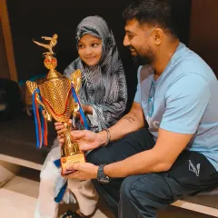 A young state champion holding her first-place trophy. This is a moment of pure joy and a testament to her incredible hard work and fighting spirit.