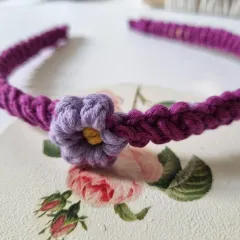This purple macrame headband features a contrasting lavender flower. The intricate knotting of the band is comfortable to wear all day.