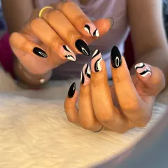 Finding beauty in the absence of color with this black and white abstract swirl design. The mix of solid black nails and patterned accents creates a bold, graphic look.