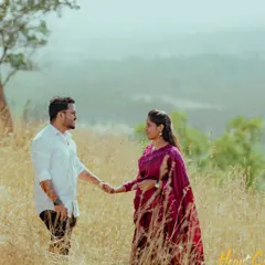 A romantic moment in a field of golden grass. The couple holds hands, their connection shining through in the warm, natural light.