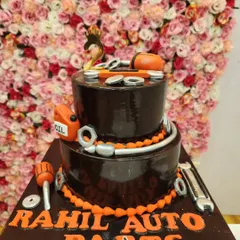 A two-tiered chocolate cake with an automobile theme. It's decorated with fondant tools, nuts, and bolts, perfect for a mechanic or car parts business.