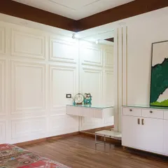Simple, stunning, and perfectly designed. This bedroom showcases a minimalist aesthetic with paneled white walls, a floating vanity, and a pop of color from the artwork.
