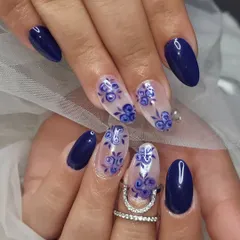 A beautiful set featuring hand-painted blue roses. The combination of solid navy blue nails and accent nails with delicate floral patterns on a clear base is classic and elegant.