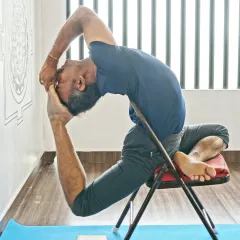 This is an advanced expression of Eka Pada Rajakapotasana, or King Pigeon Pose, using a chair for support. It shows how props can be used not just for accessibility, but to safely explore the full depth of a posture.