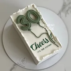Cheers to 30! A minimalist rectangular cake with trendy green balloon numbers, perfect for a modern 30th birthday celebration.
