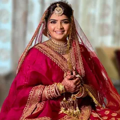 A portrait of a happy bride. This look features a classic red and gold color story, with soft contouring and a warm, glowing base to enhance her natural features and match the richness of her bridal outfit.