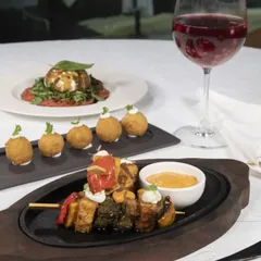 A comforting monsoon feast of hot tapas, including grilled skewers and croquettes, perfectly paired with a glass of red wine.