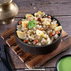 Sabudana Khichdi, a popular fasting meal, is presented here in a rustic bowl. The dark wooden textures complement the earthy tones of the dish.