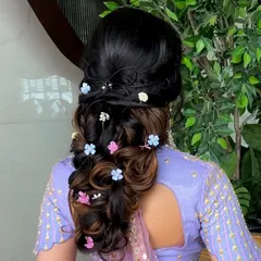 A whimsical and romantic bubble braid, adorned with colorful flowers. This hairstyle is perfect for a fun-loving bride at her Mehendi or Haldi function.