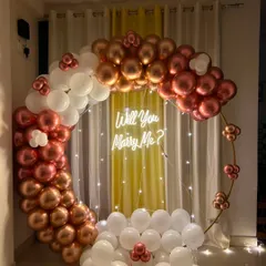 A simple yet beautiful proposal setup in your home. This circular arch with rose gold and white chrome balloons, paired with a "Will You Marry Me?" neon sign, creates the perfect backdrop for asking the big question.
