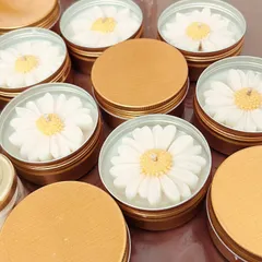My daisy candles in travel-friendly tin containers. These are perfect for bulk orders as they are durable and easy to customize.