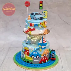 This transport-themed cake is a dream for any vehicle lover. It's a two-tier design with a light-up spacer, featuring a 3D car topper, fondant airplanes, boats, and a Thomas the Train figure circling the base.