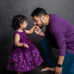 A truly precious moment between a father and his little girl, captured in our studio. The coordinated purple outfits add a touch of sparkle to this sweet, loving interaction.