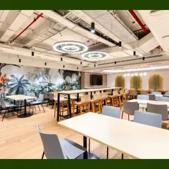 Another view of a large cafeteria space, this one featuring a beautiful nature-themed wall mural. We complemented the mural with live plants in hanging baskets and planters to create a cohesive, biophilic environment.