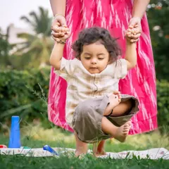 Taking those wobbly first steps with mom's helping hands. This adorable action shot captures a baby's determination and a mother's gentle support during an outdoor play session on the grass. It’s these fleeting stages of growth that I love to preserve.