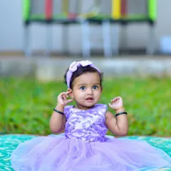 Raising her hands in a sweet, spontaneous gesture. My approach to kids photography is to let them be themselves, which results in natural and charming poses like this one.