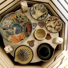 A glimpse of various pieces fresh from the kiln. You can see a hand-painted plate, a citrus juicer, and several bowls, each with its own unique glaze and character, ready to find a new home.