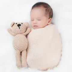 A sleeping newborn snuggled up next to a tiny teddy bear. This classic newborn pose is all about comfort, safety, and showcasing how tiny they are.