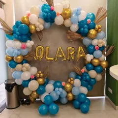 An elegant balloon ring in shades of blue, white, and gold, with dried palm leaves and small flowers. The custom name 'OLARA' makes it perfect for a birthday or baby shower.