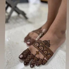 A simple and elegant henna design for the feet. This pattern features a stylish band across the foot with a lotus accent, complemented by neat, checkered designs on the toes.