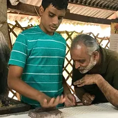 A master artisan guides a young man from our community outreach program. This mentorship is key to sustaining the craft of handblock printing for future generations in our urban ecosystem.