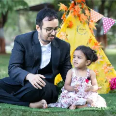 A candid shot of a father and his little daughter sharing a moment by a colorful teepee tent. These playful setups help create a fun and relaxed atmosphere for kids.