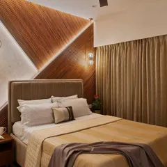 The master bedroom in this project features a striking headboard wall with geometric wood paneling and integrated accent lighting, creating a warm and inviting atmosphere.