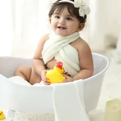 A close up shot capturing a sweet smile and a playful moment with a rubber duck. These sessions are designed to be fun, allowing us to capture your child's natural personality.