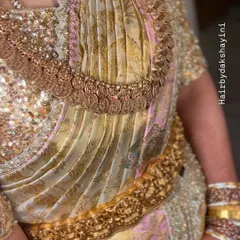The front view of the pallu pleats on a rich, textured saree. The pleats are arranged to showcase the fabric's design and are held in place perfectly by the vaddanam.