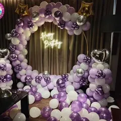 An elaborate ring decoration with purple, white, and silver chrome balloons. The floor is filled with balloons, creating an immersive and luxurious photo corner.
