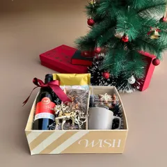 Our "Holiday Crate" sitting pretty under a Christmas tree. It's filled with wine, a festive mug, an ornament, and other treats to get you in the holiday spirit.