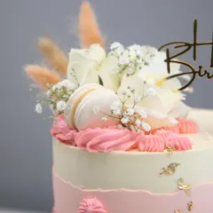 The top of the blush and gold cake, showing the beautiful arrangement of white roses, baby's breath, and dried grasses.