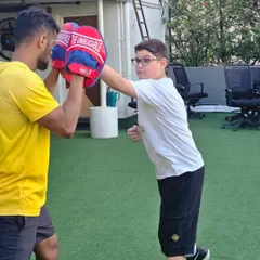 A young athlete practices a straight punch, aiming for the center of the pad. This drill hones hand-eye coordination and teaches the fundamentals of generating power from the ground up.