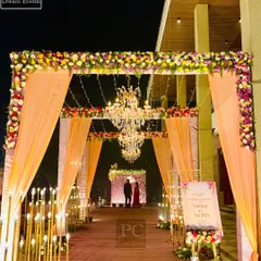 A beautiful entrance sets the tone for the entire evening. Here, I combined elegant peach-colored drapes, intricate floral arrangements, warm candle-like lighting, and grand chandeliers to create a welcoming and luxurious entryway for the guests.