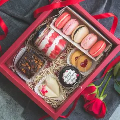 A Valentine's Day hamper filled with treats made with love. It includes a red velvet jar, assorted macarons, brownies, and a custom cupcake.