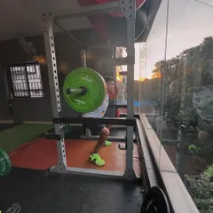 A client performs a heavy back squat with the sunset in the background.