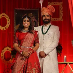 This groom is wearing an off-white Lakhnavi sherwani with delicate silver work. The outfit is completed with a georgette dupatta and styled to complement his bride's red lehenga.