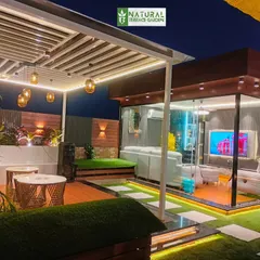 A wide shot of the Shahdara terrace, showing the seamless integration of the glass house and the open-air pergola lounge.