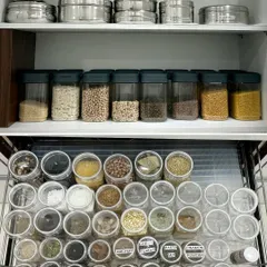 A top-down view of a perfectly organized spice drawer alongside a cabinet of decanted dals. This combination of storage solutions makes every part of the cooking process more efficient and enjoyable.