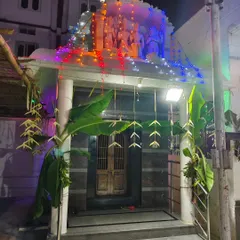 The entrance to Vasavi Matha Temple decorated for a night festival, with colorful string lights and traditional banana plantains.
