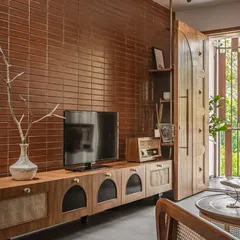 The living room's media console combines modern design with traditional materials like wood and cane webbing, set against a feature wall of stacked bricks.