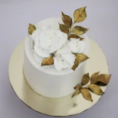 A top-down view of this elegant white and gold cake. You can see the delicate texture of the white chocolate roses and the shimmer of the gold leaves. Most often, less is more.