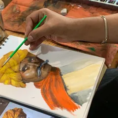 A student works on a watercolor portrait, carefully layering washes to build skin tones and capture expression. This image shows the focus and technique involved in our professional painting classes.