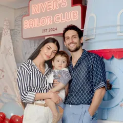 The happy family celebrating in front of the custom lighthouse and "River's Sailor Club" neon sign I designed for the event.