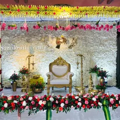 An elegant all-white backdrop made of dense jasmine flowers. The stage is framed by traditional flower pillars and accented with red roses, creating a look of pure sophistication.