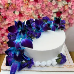 An elegant and simple design for a sophisticated celebration. This white cake is adorned with beautiful, fresh blue and purple orchids, creating a stunning visual contrast. It's a perfect example of how I use fresh flowers to elevate a classic cake design for anniversaries or milestone birthdays.