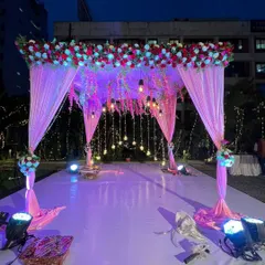 This mandap, illuminated with soft purple lighting and hanging bulbs, creates a magical ambiance for an evening wedding ceremony. It's both elegant and breathtaking.